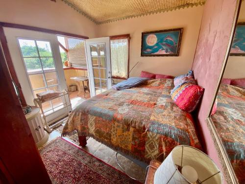 a bedroom with a bed in a room with windows at Artsy Cabin on Organic Farm in Naalehu