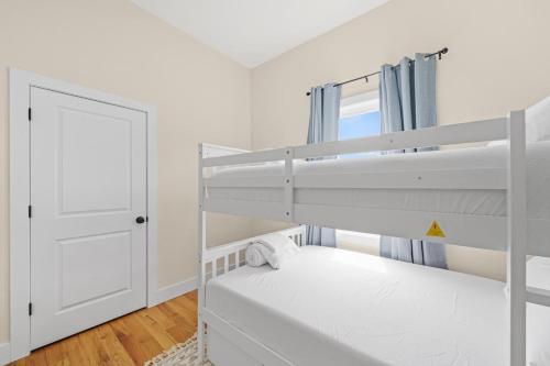 a white bedroom with a bunk bed and a door at Sky High Retreat near NYC with Rooftop! in Jersey City