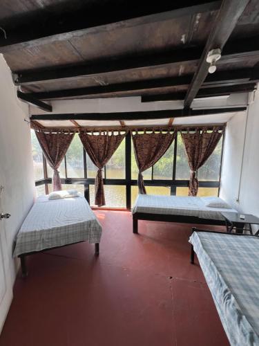 two beds in a room with a large window at Karma Muse Hotel in La Libertad