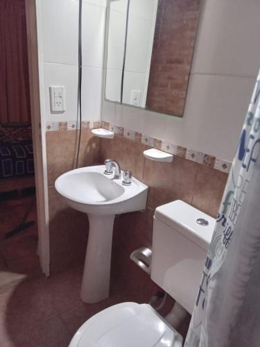 a bathroom with a sink and a toilet and a mirror at Mono Complejo Cóndor in Mina Clavero