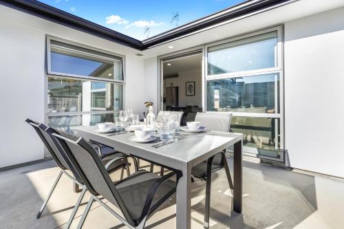a dining room with a table and chairs and windows at Stylish, Modern and Central in Hamilton