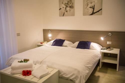 a bedroom with a large bed with white sheets and blue pillows at Hotel Roma Aparthotel in Malcesine