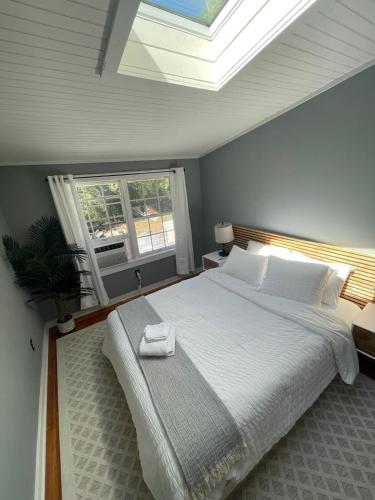 a bedroom with a large white bed with a skylight at Bright, Airy Home in Hudson! in Hudson
