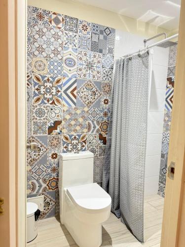 a bathroom with a toilet and a tiled wall at Lindo Dúplex Centro Histórico in Guaduas