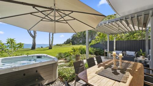 a patio with a hot tub and a table with an umbrella at Solara - Sleeps 8, Beach, Walk To Resorts, Views in Coffs Harbour
