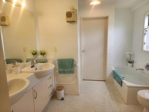 a bathroom with two sinks and a tub and a toilet at Peppertree in Tauranga