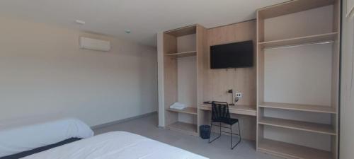 a bedroom with a bed and a desk and a television at Dormis Sinsacate in Sinsacate
