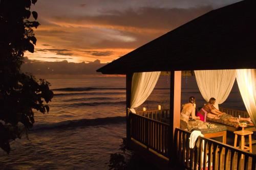 two people sitting on the porch of a house on the beach at Villa Ronggo Mayang at Balian beach in Antasari