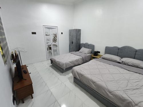 龙运Teratak Adamia Roomstay 04的有两张床和一面镜子的酒店房间