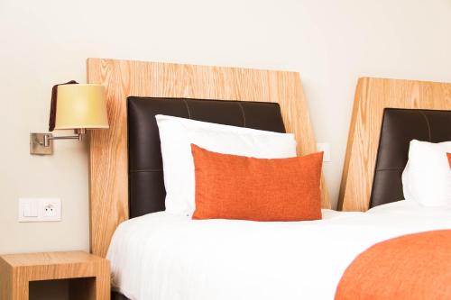 a hotel room with two beds and a orange pillow at Le Pietri Urban Hotel in Rabat
