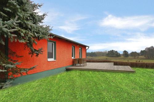 a red house with a deck and a green yard at Ferienhaus am Garder See Inselblick in Lohmen