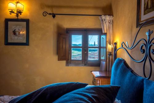 a bedroom with a window and a blue couch at Agriturismo Il Macchione in Pienza
