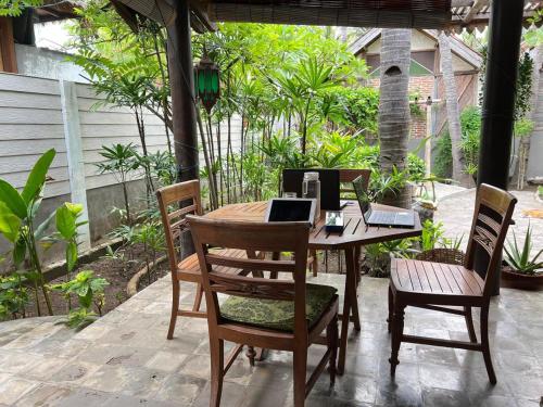 a wooden table with chairs and a laptop on it at Villas SAMALAMA Gili Trawangan in Gili Trawangan