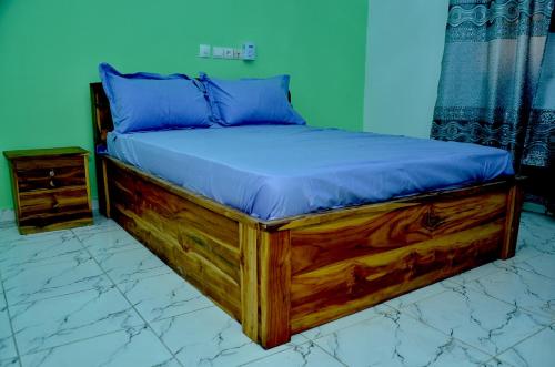 a wooden bed with blue pillows on top of it at Gosen House Zanguéra in Ablogbé