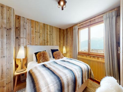 a bedroom with a bed with wooden walls and a window at Beautiful chalet in Le Bouveret with garden in Hérémence