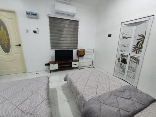龙运Teratak Adamia Roomstay 04的白色的客房配有两张床和电视。