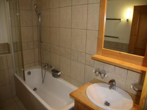 a bathroom with a sink and a tub and a mirror at Traditional apartment with balcony in Veysonnaz