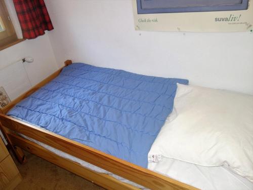 a bed with a blue comforter in a room at Apartment, 600m from cable car in Veysonnaz