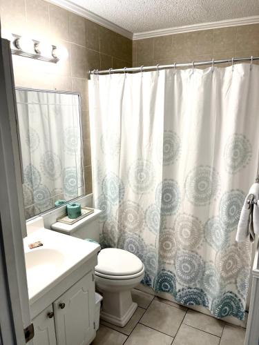 a bathroom with a toilet and a shower curtain at Life is Better Oceanside Retreat-Coligny-#233 in Hilton Head Island