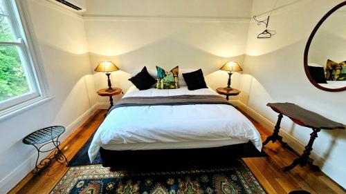 a bedroom with a bed and two lamps and a mirror at 'The Gardenia' Trentham in Trentham