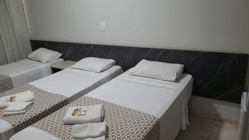 a room with three beds with towels on them at Hotel Boituva Inn - Your Hotel in Boituva