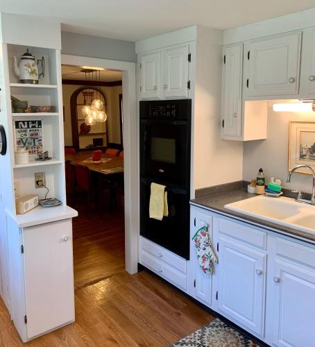 a kitchen with white cabinets and a black dishwasher at Charming 4BR colonial close to downtown in Keene