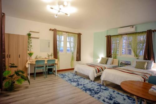 a bedroom with two beds and a table and a desk at Ban Suanlum in Bangkok