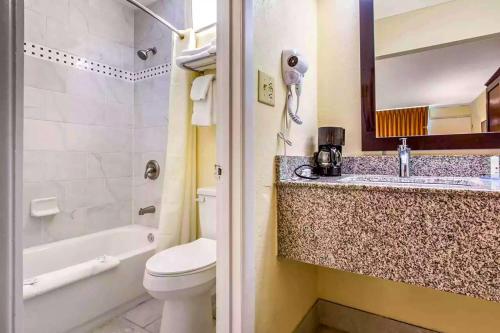 a bathroom with a toilet and a sink and a tub at Ramada by Wyndham Santee I-95 in Santee