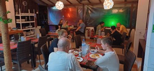 a group of people sitting at tables in a restaurant at Liberty Guesthouse Maldives in Mahibadhoo