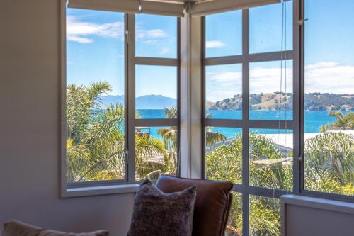 a room with large windows looking out at the ocean at The Sands - Apartment 5 - Stay Waiheke in Onetangi