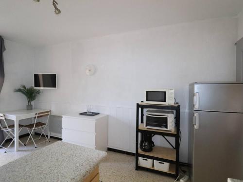 Il comprend une cuisine équipée d'un réfrigérateur et d'une table avec un four micro-ondes. dans l'établissement Studio cabine avec balcon et parking à La Grande-Motte - FR-1-307-275, à La Grande Motte