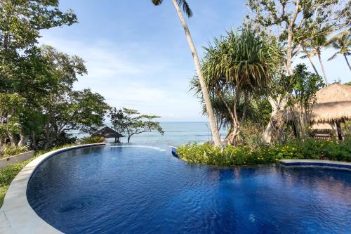 a swimming pool with a view of the ocean at Villa Ronggo Mayang at Balian beach in Antasari