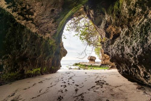 a cave on the beach with footprints in the sand at Villa Ronggo Mayang at Balian beach in Antasari
