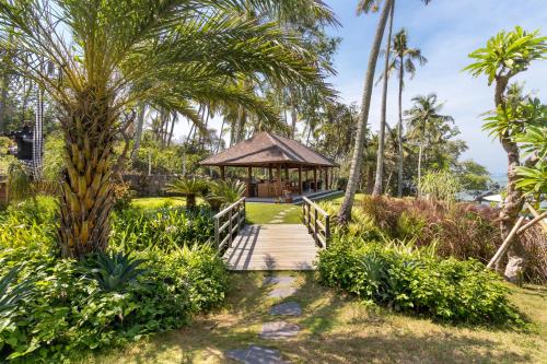 a wooden pathway leading to a gazebo with palm trees at Villa Ronggo Mayang at Balian beach in Antasari