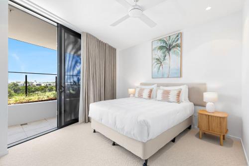 a white bedroom with a bed and a large window at Bokarina Beach Apartments, an Ascend Collection Hotel in Bokarina