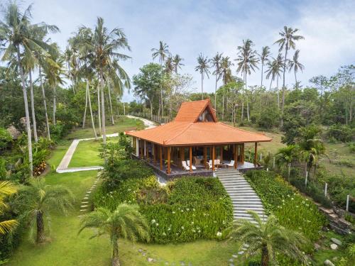 a house in the middle of a field with palm trees at Villa Ronggo Mayang at Balian beach in Antasari