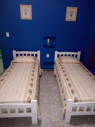 two beds in a room with a blue wall at Alojamiento EL DESCANSO in Olavarría