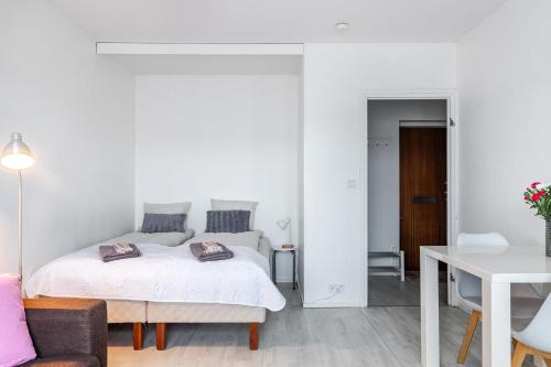 a white bedroom with a bed and a table at Compact Studio with Balcony next to Railway Station in Lahti