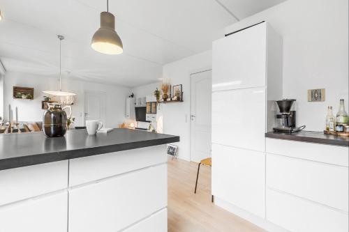 a kitchen with white cabinets and black countertops at Ryethave lejlighed ved Ryetvej i Værløse in Værløse