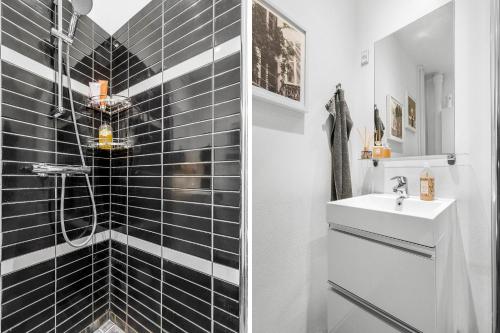 a bathroom with black tiled walls and a sink at Ryethave lejlighed ved Ryetvej i Værløse in Værløse