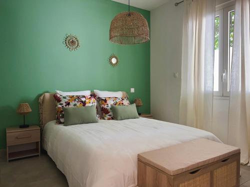 a bedroom with a large bed with green walls at Villa Tropéa in Les Cocos