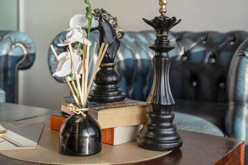 tres jarrones negros en una mesa con libros y flores en The Tarantino - Grampian Lettings, en Aberdeen