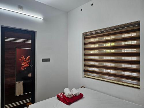 a bedroom with a bed and a window with towels at MetroNova Homes - Furnished stay in Ambalappuzha in Alleppey