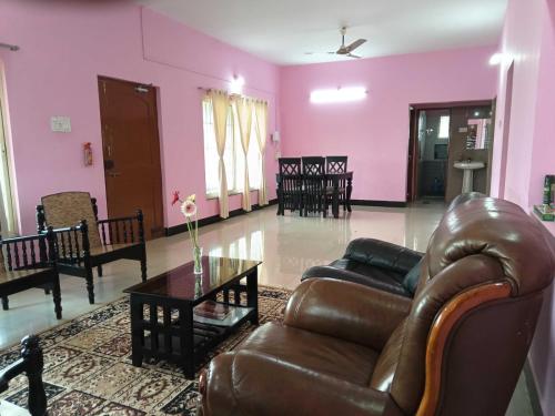 a living room with a leather couch and a table at Hotel Baba Inn, Lodge in Belgaum