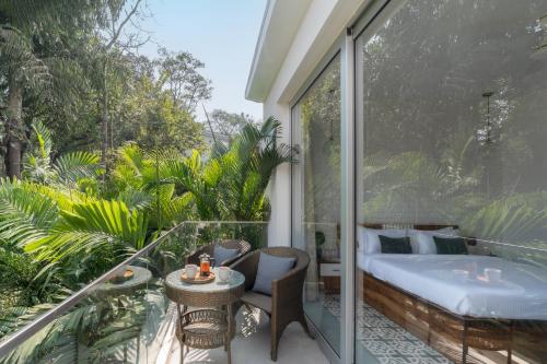 a room with a balcony with a bed and a table at La Olalian 2 & 3 BHK Designer Villas Near Anjuna Beach with Private Pool & Sun Deck & Garden in Anjuna