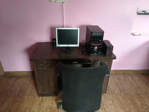 a desk with a computer and a monitor on it at Hotel Baba Inn, Lodge in Belgaum