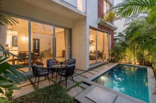 a patio with a table and chairs next to a swimming pool at La Olalian 2 & 3 BHK Designer Villas Near Anjuna Beach with Private Pool & Sun Deck & Garden in Anjuna