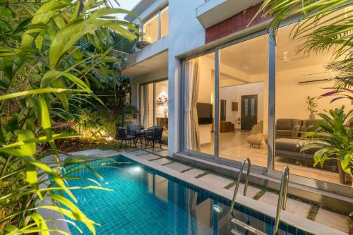 a house with a swimming pool and a living room at La Olalian 2 & 3 BHK Designer Villas Near Anjuna Beach with Private Pool & Sun Deck & Garden in Anjuna
