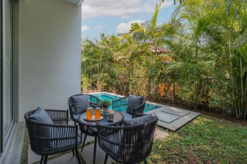 a patio with a table and chairs and a pool at La Olalian 2 & 3 BHK Designer Villas Near Anjuna Beach with Private Pool & Sun Deck & Garden in Anjuna