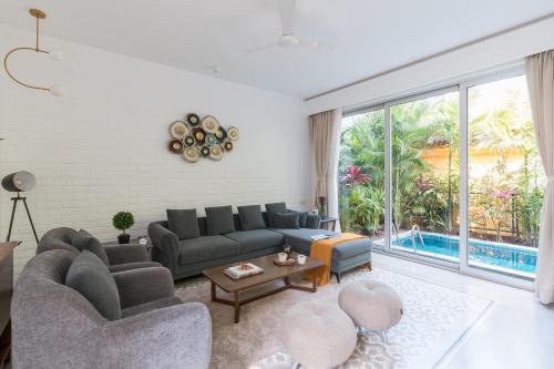 a living room with two couches and a pool at La Olalian 2 & 3 BHK Designer Villas Near Anjuna Beach with Private Pool & Sun Deck & Garden in Anjuna